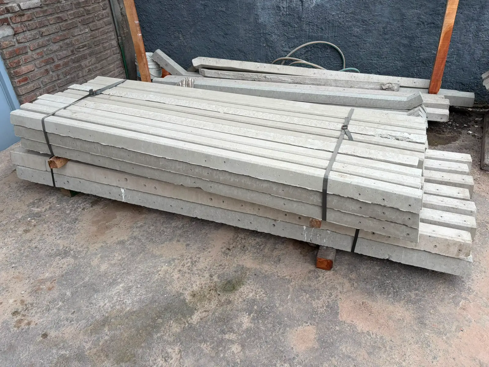 Fardos de postes rectos de hormigón atados con fleje, apilados en el patio del depósito
